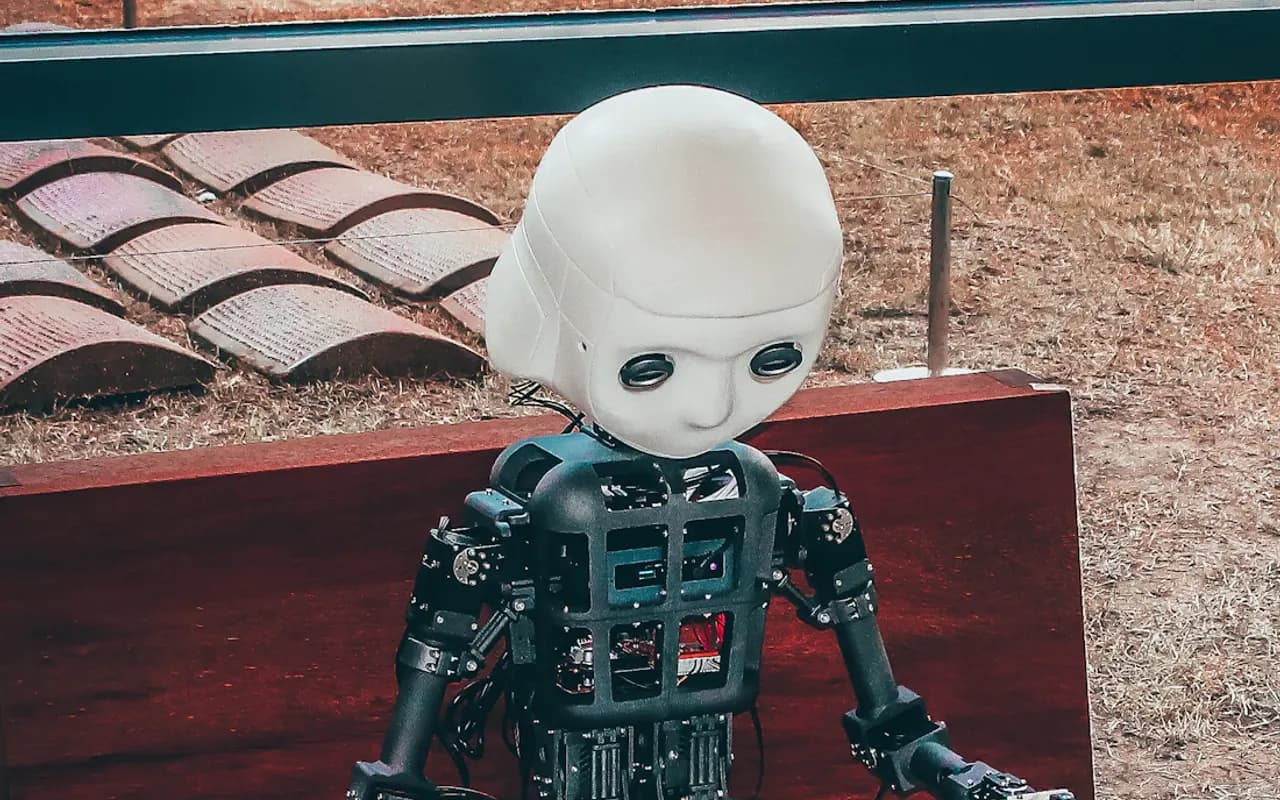 A small humanoid robot sitting on a bench, close view